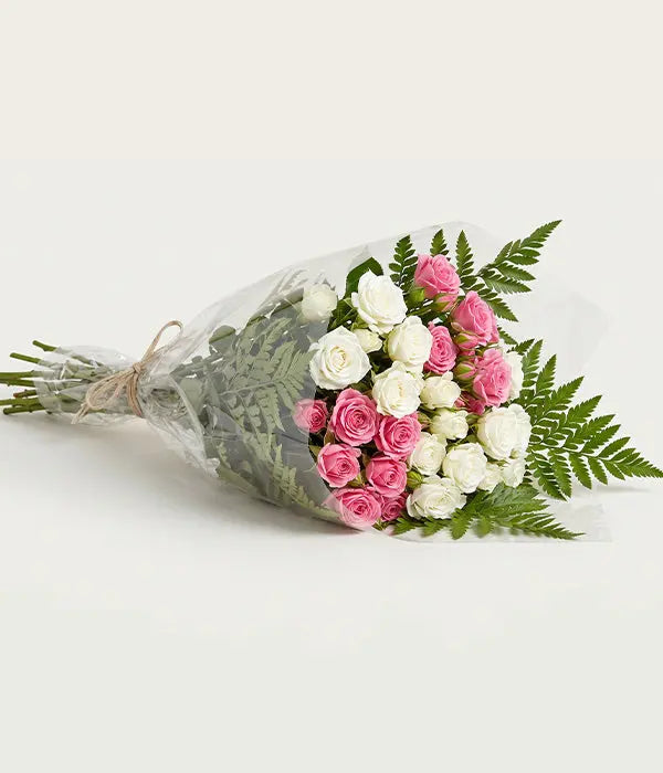 50 blooms of white and pink spray roses with greenery in a clear wrapped bouquet by Send Blooms
